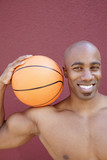 Photo: Portrait of a happy African American man with basketball on shoulder over colored background Portrait of a happy African American man with basketball on shoulder over colored background