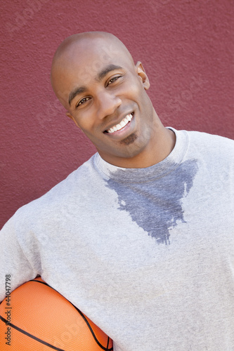 Photo: Portrait of a happy young African American man with basketball over colored background Portrait of a happy young African American man with basketball over colored background