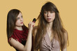 Portrait of a young female model getting her hair styled over colored background