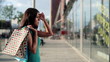 Woman with shopping bags looking at shop window, steadicam shot