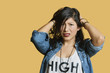 Portrait of a frustrated young woman with hands in hair over colored background