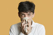 Portrait of a young man blowing nose over colored background