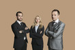 Portrait of young business people with arms crossed over colored background