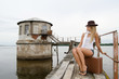 The beautiful young woman with a suitcase at a pier