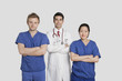 Photo: Portrait of diverse healthcare workers standing with hands folded over gray background Portrait of diverse healthcare workers standing with hands folded over gray background