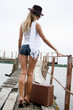 The beautiful young woman with a suitcase at a pier