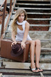 The beautiful woman with a suitcase on an old ladder