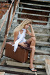 The beautiful woman with a suitcase on an old ladder