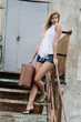 The beautiful woman with a suitcase on an old ladder