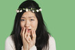 Portrait of a young woman expressing fear and anxiety over green background