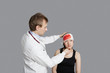 Male doctor treating female patient over colored background