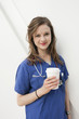 Photo: Portrait of a beautiful female doctor holding a disposable cup over colored background Portrait of a beautiful female doctor holding a disposable cup over colored background