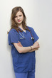 Portrait of a female surgeon standing with arms crossed over colored background