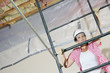 Young female construction worker climbing on scaffold