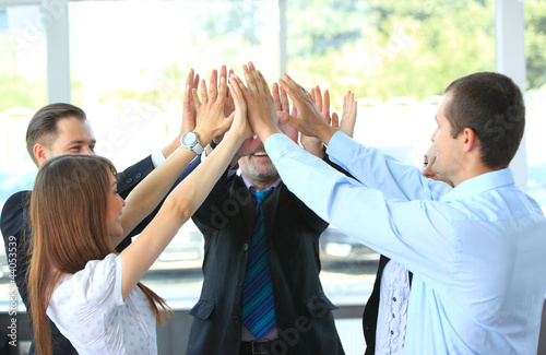 Photo: Business team celebrating their success with a high five Business team celebrating their success with a high five