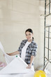 Portrait of mid adult architect holding blueprints at construction site