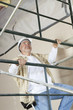 Front view of mature man climbing scaffold