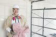 Portrait of mature man holding sponge with dust mask in neck