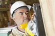 Photo: Serious male construction worker cutting wood with a power saw Serious male construction worker cutting wood with a power saw