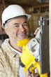 Photo: Portrait of a smiling male construction worker cutting wood with a circular saw Portrait of a smiling male construction worker cutting wood with a circular saw