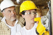 Photo: Female worker cutting wood with a power saw while male worker standing behind Female worker cutting wood with a power saw while male worker standing behind