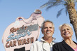Portrait of a happy mature couple in front of car wash signboard