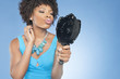 Photo: Attractive African American woman puckering while looking in mirror over colored background Attractive African American woman puckering while looking in mirror over colored background