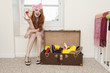 Photo: Portrait of young woman sitting near window showing high heels with suitcase full of footwear Portrait of young woman sitting near window showing high heels with suitcase full of footwear