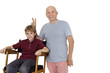 Photo: Portrait of senior man gesturing peace sign while pre-teen boy sitting on director's chair over white background Portrait of senior man gesturing peace sign while pre-teen boy sitting on director's chair over white background
