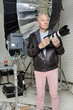 Front view of senior man with camera in photographer's studio