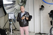 Portrait of happy senior photographer with camera in studio