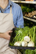 Photo: Midsection of man holding basket of green onion in supermarket Midsection of man holding basket of green onion in supermarket