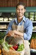 Photo: Portrait of handsome young salesperson standing with basket full of vegetables Portrait of handsome young salesperson standing with basket full of vegetables