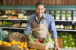 Photo: Portrait of a happy young salesman with vegetable basket in supermarket Portrait of a happy young salesman with vegetable basket in supermarket