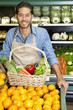 Photo: Portrait of a happy man with vegetable basket standing near oranges stall in supermarket Portrait of a happy man with vegetable basket standing near oranges stall in supermarket