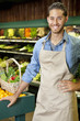 Photo: Handsome young sales clerk standing near stall in supermarket Handsome young sales clerk standing near stall in supermarket