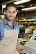 Photo: Portrait of handsome store employee standing near cash register in supermarket Portrait of handsome store employee standing near cash register in supermarket