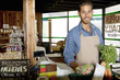 Photo: Portrait of handsome young store clerk holding vegetable in supermarket Portrait of handsome young store clerk holding vegetable in supermarket