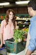 Photo: Beautiful young woman looking at store clerk in supermarket Beautiful young woman looking at store clerk in supermarket