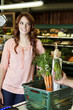 Photo: Happy young woman looking away while hand holding vegetable in supermarket Happy young woman looking away while hand holding vegetable in supermarket