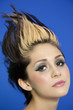 Photo: Close-up portrait of beautiful young woman with spiked hair over blue background Close-up portrait of beautiful young woman with spiked hair over blue background