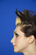 Photo: Side view of young woman with spiked hair over colored background Side view of young woman with spiked hair over colored background
