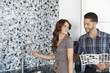 Beautiful young couple standing model home kitchen with color samples