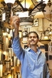 Happy young man looking at price tag of chandelier in lights store