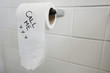 Close-up of toilet paper with text in bathroom