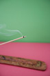 Close-up view of incense stick burning over colored background