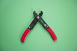 Close-up view of duckbill pliers over green background