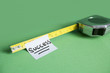 Close-up of sticky note stuck to measuring tape over colored background
