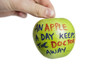 Photo: Cropped image of hand holding a granny smith apple with sayings text over white background Cropped image of hand holding a granny smith apple with sayings text over white background
