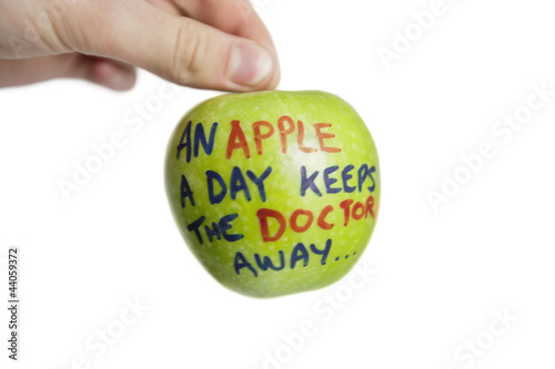 Photo: Cropped image of hand holding a granny smith apple with sayings text over white background Cropped image of hand holding a granny smith apple with sayings text over white background